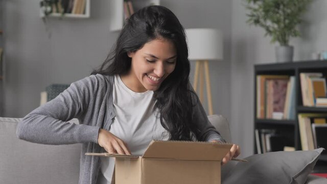 happy woman sits on the couch open online order cardboard box,satisfied female customer opening,unboxing postal parcel package,home shipping delivery concept