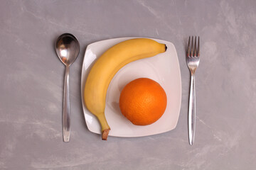 Ripe bananas and orange on a wooden table