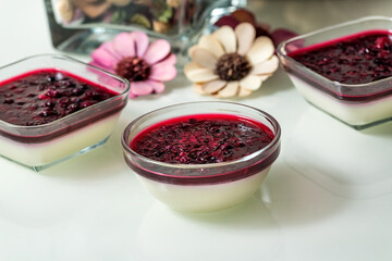Delicious panna cotta with with raspberry sauce on white table