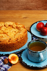 Closeup homemade pie with nectarines and cup of tea on wooden table. Shallow focus.