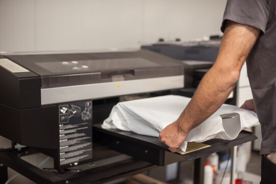 Graphic print technician work on digital t-shirt printing machine printer