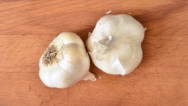 Fresh garlic bulbs dancing on a wooden cutting board, stop motion animation