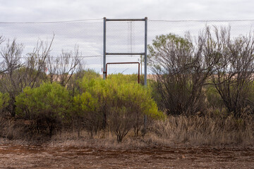 The fence door in an overgrown abandoned tennis court