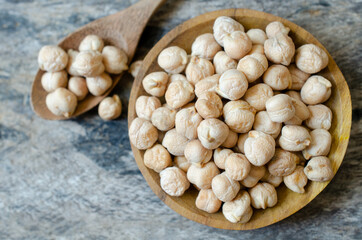 Top view of dry organic raw chick pea or garbanzo bean seed pile in wooden bowl and spoon on grunge background
