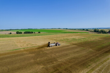 The tractor scatters manure on the field. Feeding the soil before harrowing. View from above.