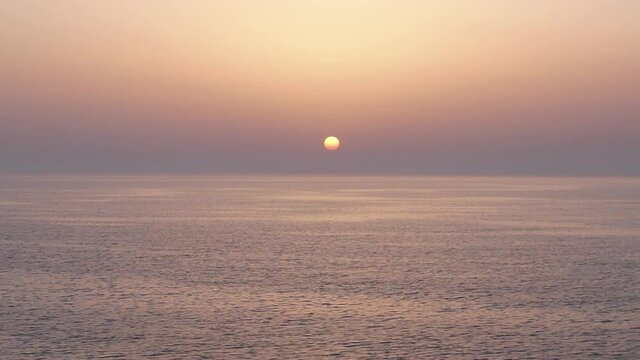 Plan de drone minimaliste au dessus de la mer avec le coucher de soleil en arri&egrave;re-plan et un petit bateau qui passe