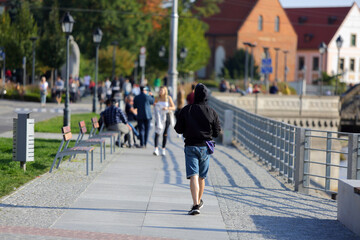 Młody mężczyzna idzie chodnikiem wzdłuż kanału we Wrocławiu.