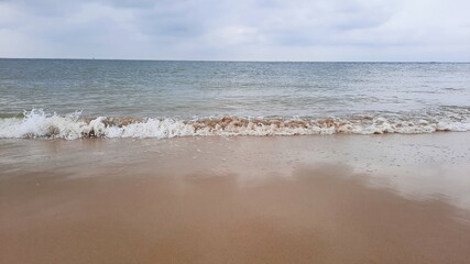 Vague sur une plage de la mer du Nord sur fond de ciel nuageux