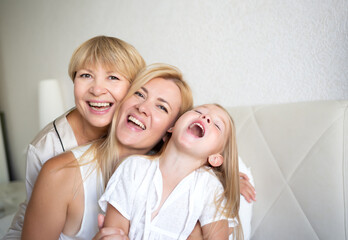 family portrait: mom, daughter and granddaughter are sitting on the bed
