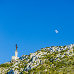 Croix de Provence cross at the top of the Montagne Sainte-Victoire mountain with a moon in the blue...