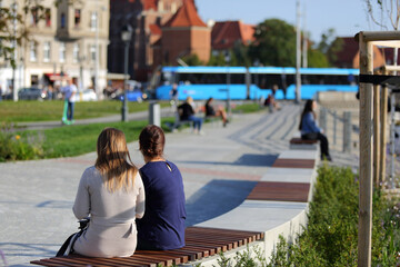 Dwie kobiety siedzą na ławkach nad rzeką Odrą we Wrocławiu. - obrazy, fototapety, plakaty