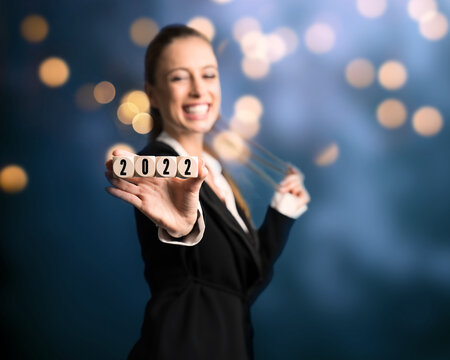 young woman with cubes and message 2022 in front of colorful lights background
