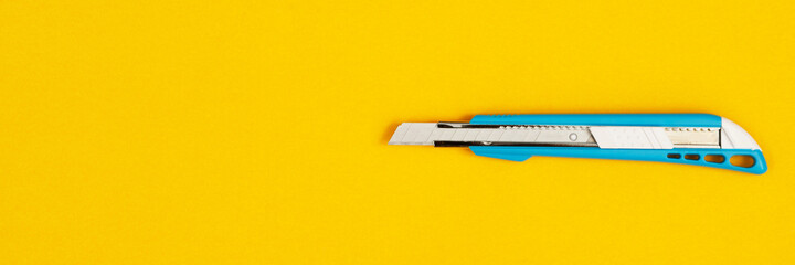 A blue cutter knife placed on a yellow background