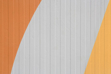 Grey vertical striped walls with orange painted geometric shapes. Exterior design, metallic panels.