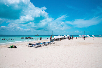 Obraz premium Cancun, Mexico. May 30, 2021. Deckchairs under canopy shade for resting on beach sand in front of sea with yachts. Tourists enjoying beach summer holiday