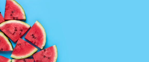 Slices of juicy red watermelon on blue. Top view, flat lay. Banner