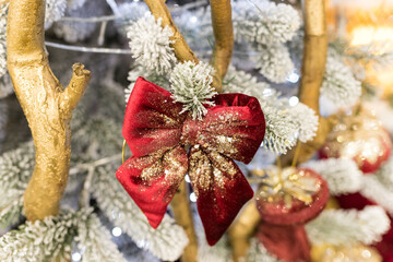 Close up of holidays location with red gold toys, garlands and bow on Christmas tree