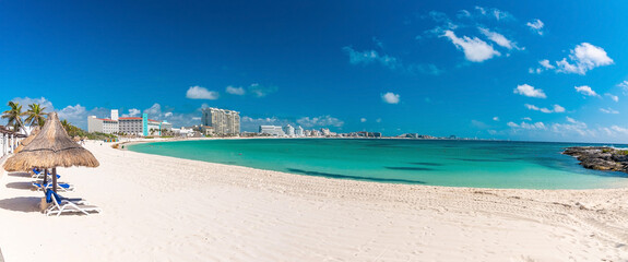 Cancun, Mexico. May 30, 2021. Empty deck chairs under straw roof canopy on sand at beach with...