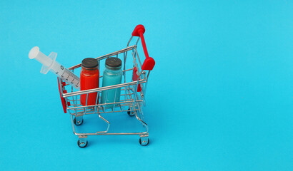 Shopping cart with vaccine vials bottles and syringes for vaccination against coronavirus.