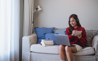 A young woman with headphone using laptop computer for online study at home