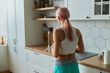 Woman fitness blogger with tattoo on back shoots video about healthy nutrition in kitchen