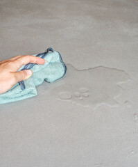 hand cleaning spilled water on a cement floor with a cloth dishcloth drops on a concrete floor, microcement wet waterproof cement surface