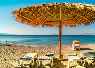 Resting and relaxing deck chairs and sunshade  are waiting for tourists on sandy beach of the Red Sea, Middle East