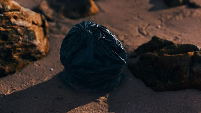 black plastic garbage bags full of trash on the beach