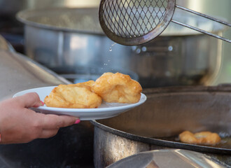 Dough donuts are fried in oil. A cafe
