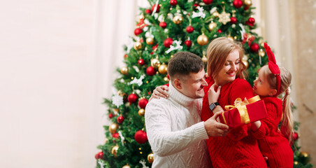 A family exchanges gifts on Christmas Eve at a festively decorated Christmas tree