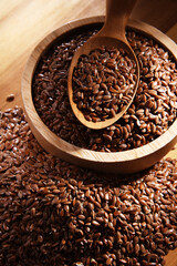 Bowl of brown flax seeds on wooden table