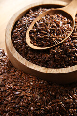 Bowl of brown flax seeds on wooden table