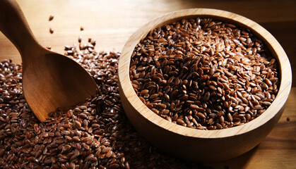 Bowl of brown flax seeds on wooden table
