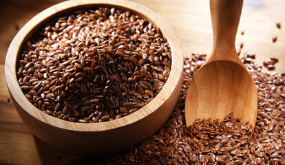 Bowl of brown flax seeds on wooden table