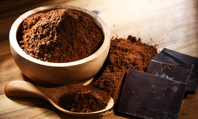 Composition with bowl of cocoa powder on wooden table