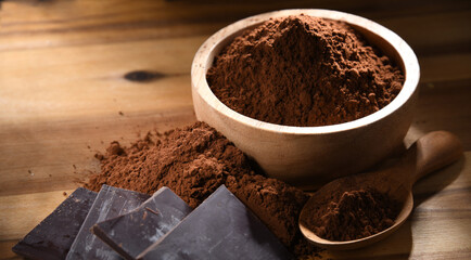 Composition with bowl of cocoa powder on wooden table