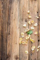 Getrocknete Blütenblätter einer Rose auf Untergrund aus Holz – rustikale Dekoration