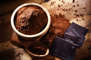 Composition with bowl of cocoa powder on wooden table