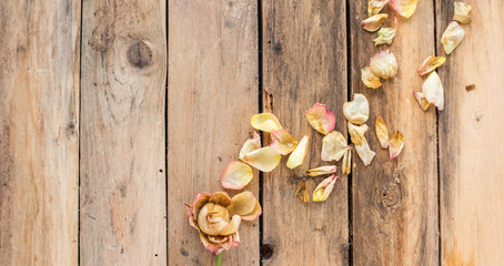 Getrocknete Blütenblätter einer Rose auf Untergrund aus Holz – rustikale Dekoration