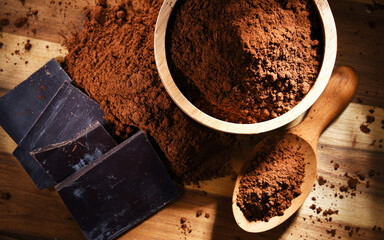 Composition with bowl of cocoa powder on wooden table