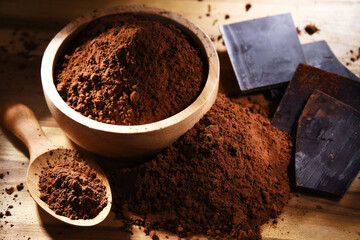 Composition with bowl of cocoa powder on wooden table