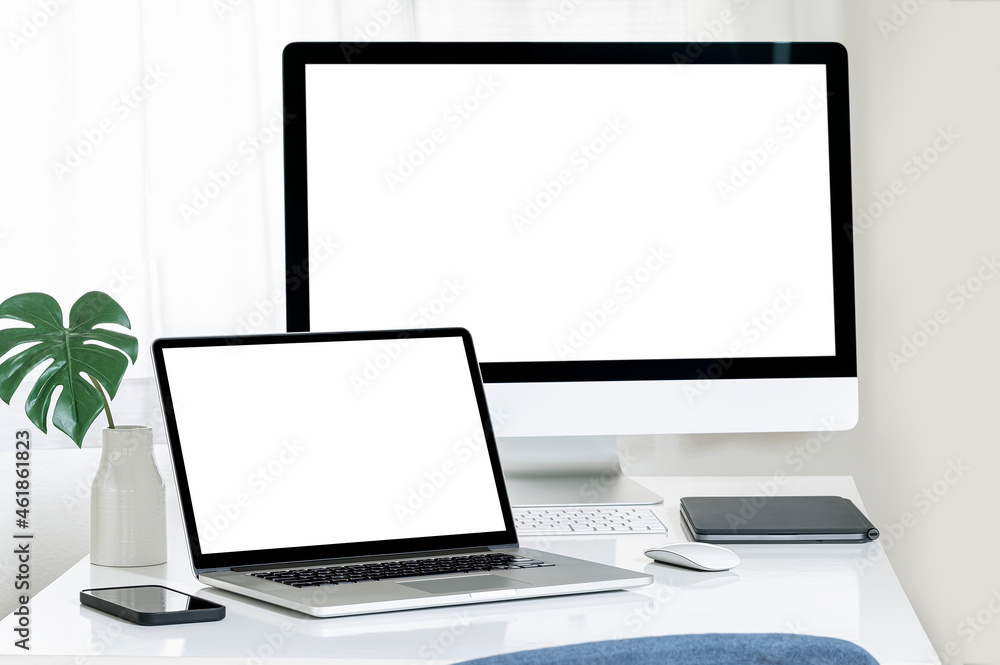 Poster mockup blank white screen laptop computer and desktop computer on white table.