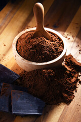 Composition with bowl of cocoa powder on wooden table