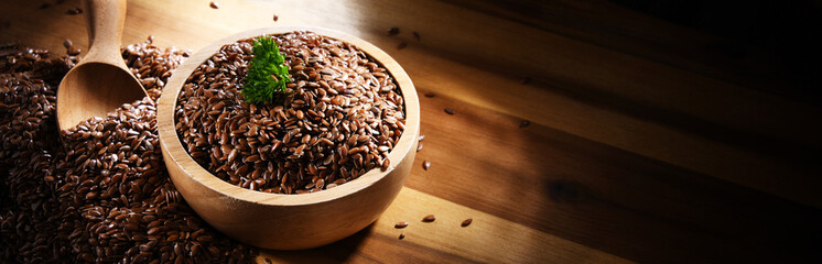 Bowl of brown flax seeds on wooden table