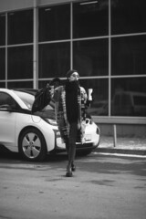 Fototapeta na wymiar Woman drinking coffee and charging electro car