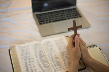 Woman hand praying on holy bible in the morning. Study bible with online worship.