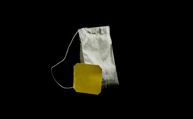 Tea bag with yellow tag, isolated on black background.