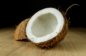 Coconut on a wooden table. Two halves of a broken coconut.