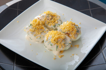 Huevos rellenos de atún con mahonesa sobre plato de porcelana blanca. Tuna stuffed eggs with mayonnaise on a white porcelain plate.