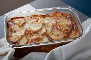 Patatas asadas con bechamel y queso en  fuente de cristal. Roasted potatoes with béchamel sauce and cheese in a glass dish